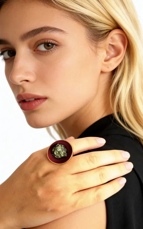 , Ανακαλύψτε τη μαγεία του χειροποίητου κοσμήματος με αυτό το εντυπωσιακό γυναικείο δαχτυλίδι με πυρίτη σε μπορντό απόχρωση. Σχεδιασμένο από την Ελληνίδα Σχεδιάστρια Κοσμημάτων Αικατερίνη Χαλκιαδάκη, το δαχτυλίδι αυτό συνδυάζει την παραδοσιακή ελληνική τεχνοτροπία με τη σύγχρονη αισθητική.
Το μεγάλο δαχτυλίδι διαθέτει στρογγυλή επιφάνεια σε έντονο μπορντό χρώμα, στο κέντρο της οποίας λάμπει φυσικός σιδηροπυρίτης με το χαρακτηριστικό του χρυσαφί μεταλλικό γυαλάδι. Η βάση από ορείχαλκο προσφέρει σταθερότητα και άνεση στη φορεσιά, ενώ η χειροποίητη κατασκευή εγγυάται τη μοναδικότητα κάθε κομματιού.
Αυτό το statement δαχτυλίδι είναι ιδανικό για να συμπληρώσει τόσο καθημερινά όσο και βραδινά σύνολα, προσδίδοντας μια πινελιά αυθεντικής ελληνικής τέχνης στο στυλ σας. Φυλάσσετε σε στεγνό μέρος και καθαρίζετε με μαλακό πανί για να διατηρήσετε τη λάμψη του κοσμήματος.