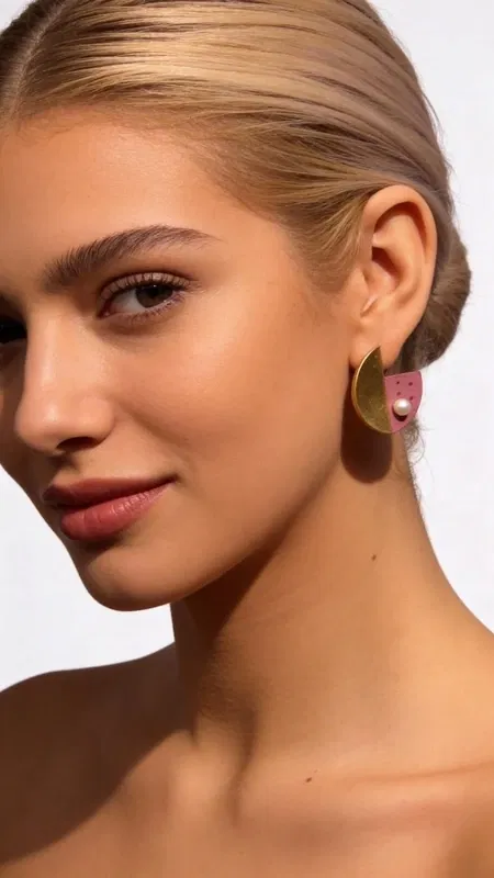 , Ανακαλύψτε τη μοναδική ομορφιά των καρφωτών σκουλαρικιών με μαργαριτάρια και ροζ χρώμα, ένα εντυπωσιακό κόσμημα που συνδυάζει τη σύγχρονη αισθητική με την κλασική κομψότητα. Αυτά τα χειροποίητα σκουλαρίκια από την Ελληνίδα Σχεδιάστρια Κοσμημάτων Αικατερίνη Χαλκιαδάκη διακρίνονται για τη γεωμετρική τους φόρμα και τον εντυπωσιακό συνδυασμό χρωμάτων που προσφέρουν.
Κατασκευασμένα από premium ορείχαλκο και διακοσμημένα με φυσικές πέρλες, αυτά τα γυναικεία σκουλαρίκια παρουσιάζουν μια πρωτότυπη aesthetic που ξεχωρίζει. Η ροζ απόχρωση συνδυάζεται αρμονικά με τις χρυσαφί λεπτομέρειες, δημιουργώντας ένα boho chic look που ενισχύει κάθε outfit. Ιδανικά για καθημερινή χρήση αλλά και για ειδικές περιστάσεις.