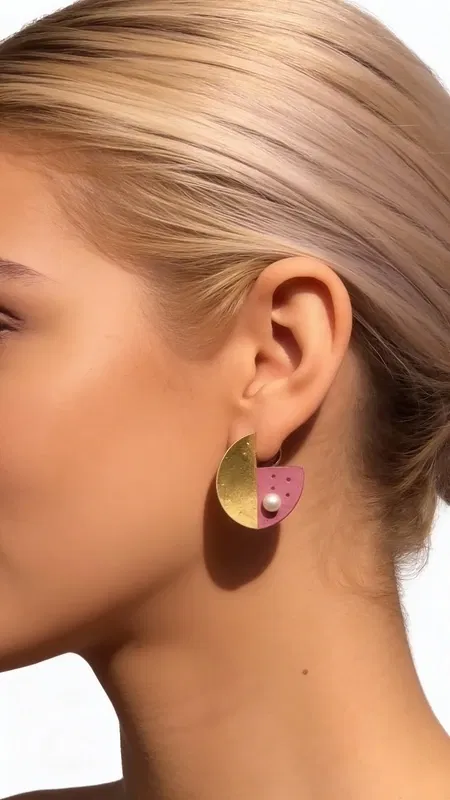 , Ανακαλύψτε τη μοναδική ομορφιά των καρφωτών σκουλαρικιών με μαργαριτάρια και ροζ χρώμα, ένα εντυπωσιακό κόσμημα που συνδυάζει τη σύγχρονη αισθητική με την κλασική κομψότητα. Αυτά τα χειροποίητα σκουλαρίκια από την Ελληνίδα Σχεδιάστρια Κοσμημάτων Αικατερίνη Χαλκιαδάκη διακρίνονται για τη γεωμετρική τους φόρμα και τον εντυπωσιακό συνδυασμό χρωμάτων που προσφέρουν.
Κατασκευασμένα από premium ορείχαλκο και διακοσμημένα με φυσικές πέρλες, αυτά τα γυναικεία σκουλαρίκια παρουσιάζουν μια πρωτότυπη aesthetic που ξεχωρίζει. Η ροζ απόχρωση συνδυάζεται αρμονικά με τις χρυσαφί λεπτομέρειες, δημιουργώντας ένα boho chic look που ενισχύει κάθε outfit. Ιδανικά για καθημερινή χρήση αλλά και για ειδικές περιστάσεις.