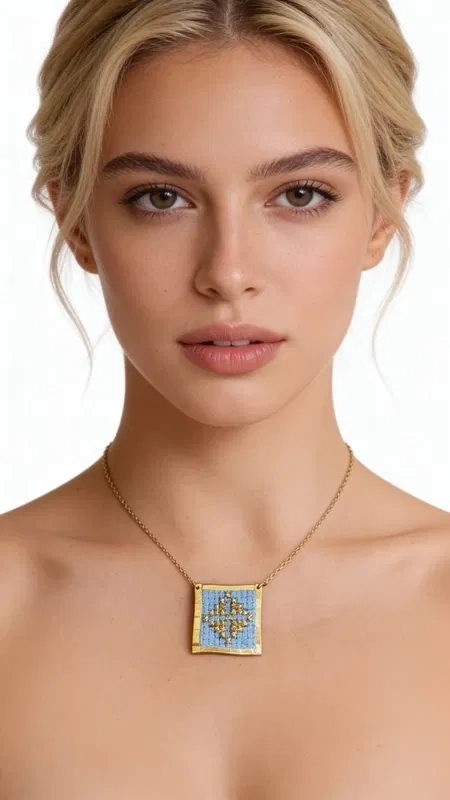 Αυτό το εξαιρετικό κεντητό κολιέ σε γαλάζιο χρώμα με γεωμετρικά σχέδια αποτελεί έναν μοναδικό συνδυασμό παραδοσιακής τέχνης και σύγχρονου design. Σχεδιασμένο από την Ελληνίδα Σχεδιάστρια Κοσμημάτων Αικατερίνη Χαλκιαδάκη, κάθε λεπτομέρεια κεντήθηκε στο χέρι με χρυσοκλωστή σε φόντο γαλάζιου υφάσματος, δημιουργώντας ένα κόσμημα που ξεχωρίζει.
Το τετράγωνο κεντητό μοτίβο φέρει πολύχρωμα γεωμετρικά σχέδια που παραπέμπουν στο ελληνικό folklore, ενώ το χρυσό πλαίσιο από ορείχαλκο προσδίδει κομψότητα και αντοχή. Η λεπτή χρυσή αλυσίδα καθιστά το κολιέ ιδανικό για καθημερινή ή βραδινή εμφάνιση.
Αυτό το statement κολιέ συνδυάζεται τέλεια με μονόχρωμα outfits, προσθέτοντας χρώμα και χαρακτήρα στο look σας. Η χειροποίητη κατασκευή και τα ποιοτικά υλικά εγγυώνται τη μακροζωία του κοσμήματος.
Φυλάσσετε το κολιέ σε στεγνό χώρο και καθαρίζετε απαλά με μαλακό πανί για να διατηρήσετε τα ζωηρά χρώματα του κεντήματος.