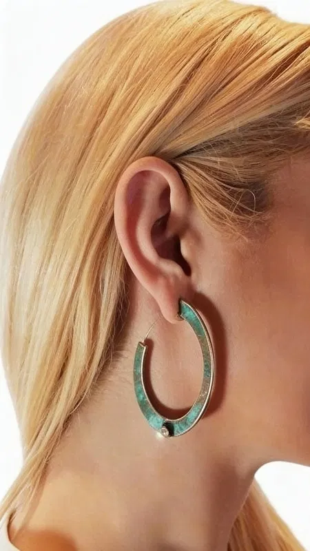 , Εντυπωσιακά σκουλαρίκια κρίκοι με μαργαριτάρια που συνδυάζουν τη φυσική ομορφιά του χαλκού με την κομψότητα των πέρλων. Αυτά τα μεγάλα καρφωτά σκουλαρίκια, σχεδιασμένα από την Ελληνίδα Σχεδιάστρια Κοσμημάτων Αικατερίνη Χαλκιαδάκη, διαθέτουν μοναδική πράσινη πατίνα που προσδίδει vintage χαρακτήρα και αυθεντικότητα.
Κάθε σκουλαρίκι φέρει μία λευκή πέρλα τοποθετημένη στρατηγικά στο κάτω μέρος του κρίκου, δημιουργώντας ένα τέλειο contrast με την οξειδωμένη επιφάνεια του χαλκού. Η χειροποίητη κατασκευή και η φυσική πατίνα καθιστούν κάθε ζεύγος μοναδικό, ενώ ο ανοιχτός σχεδιασμός του κρίκου προσφέρει άνεση και στυλ.
Ιδανικά για γυναίκες που αγαπούν τα statement κοσμήματα με boho στοιχεία, αυτά τα σκουλαρίκια ολοκληρώνουν τόσο casual όσο και επίσημα looks. Η κλασική φόρμα του κρίκου σε συνδυασμό με την πέρλα τα καθιστά κατάλληλα για γάμους, ειδικές περιστάσεις και καθημερινή χρήση.