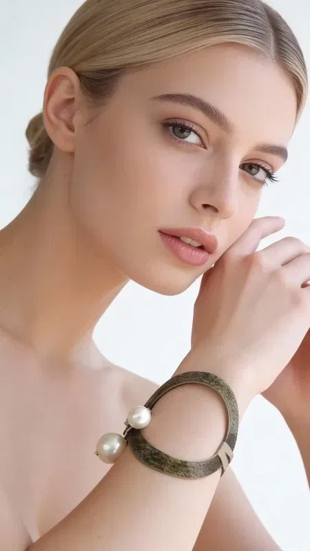 Ξεχωρίστε με αυτό το εντυπωσιακό statement βραχιόλι που συνδυάζει τη μαγεία των μαργαριταριών με το μυστήριο του μαύρου χρώματος. Σχεδιασμένο από την Ελληνίδα Σχεδιάστρια Κοσμημάτων Αικατερίνη Χαλκιαδάκη, αυτό το χειρόγραφο κόσμημα αποτελεί την τέλεια επιλογή για γυναίκες που αγαπούν να κάνουν δυναμική εμφάνιση.
Το μεγάλο βραχιόλι διαθέτει έναν μοναδικό συνδυασμό μαύρης βάσης με λευκές πέρλες που δημιουργούν εκπληκτική αντίθεση. Η χειροποίητη κατασκευή του εξασφαλίζει μοναδικότητα σε κάθε κομμάτι, ενώ το statement design του προσδίδει άμεσα κομψότητα σε κάθε εμφάνιση. Η εργονομική του φόρμα εφαρμόζει άνετα στον καρπό, κάνοντάς το ιδανικό για καθημερινή ή βραδινή χρήση.
Συνδυάστε το με απλά outfits για να αναδείξετε τη μοναδικότητά του ή φορέστε το σε ειδικές περιστάσεις για extra glamour. Φροντίστε το με μαλακό πανί και αποφύγετε την επαφή με χημικά για να διατηρήσετε την ομορφιά των μαργαριταριών.