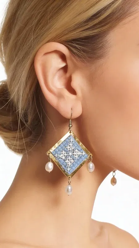 , Τα statement κεντητά σκουλαρίκια σε γαλάζιο χρώμα με γεωμετρικά σχέδια από χρυσοκλωστή αποτελούν το ιδανικό χειροποίητο κόσμημα για να αναδείξετε τη μοναδικότητά σας. Αυτά τα εντυπωσιακά κρεμαστά σκουλαρίκια, σχεδιασμένα από την Ελληνίδα Σχεδιάστρια Κοσμημάτων Αικατερίνη Χαλκιαδάκη, συνδυάζουν την παραδοσιακή τέχνη του κεντήματος με μοντέρνα αισθητική.
Η γαλάζια απόχρωση σε συνδυασμό με τη χρυσοκλωστή δημιουργεί μια εκλεπτυσμένη αντίθεση που προσελκύει τα βλέμματα. Τα γεωμετρικά σχέδια προσδίδουν σύγχρονο χαρακτήρα, ενώ οι λεπτές πέρλες που κρέμονται από τη βάση των σκουλαρικιών προσθέτουν κίνηση και θηλυκότητα. Το folklore design τους τα καθιστά ιδανικά για ιδιαίτερες στιγμές, από νυφικές εμφανίσεις έως κοκτέιλ παρτυ. Ιδανικά σκουλαρίκαι για γάμους, βαπτίσεις και ιδιαίτερες εκδηλώσεις. Συντηρείστε τα με προσοχή, αποφεύγοντας την επαφή με νερό και αρώματα για μεγαλύτερη διάρκεια ζωής.