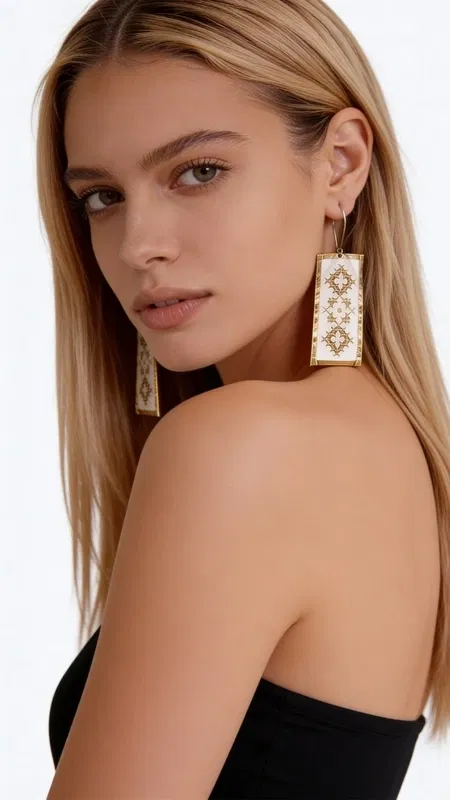 , Αυτά τα εντυπωσιακά statement σκουλαρίκια κεντητά με χρυσοκλωστή συνδυάζουν την παραδοσιακή τέχνη του κεντήματος με τη σύγχρονη αισθητική. Σχεδιασμένα από την Ελληνίδα Σχεδιάστρια Κοσμημάτων Αικατερίνη Χαλκιαδάκη, αυτά τα χειροποίητα σκουλαρίκια διακοσμούνται με γεωμετρικά μοτίβα σε λευκή βάση που δημιουργούν μια κομψή και διαχρονική εμφάνιση.
Τα κρεμαστά σκουλαρίκια χαρακτηρίζονται από τη λεπτομερή χρυσή κεντητή διακόσμηση που σχηματίζει ρομβοειδή σχέδια, προσφέροντας μια μοναδική υφή και όγκο. Η λευκή βάση δημιουργεί την τέλεια αντίθεση με τις χρυσές λεπτομέρεις, ενώ το ορθογώνιο σχήμα τους τα καθιστά ιδανικά για κάθε περίσταση.
Αυτά τα μοντέρνα κεντητά σκουλαρίκια είναι η τέλεια επιλογή για γυναίκες που αγαπούν τα εντυπωσιακά κοσμήματα με παραδοσιακά στοιχεία. Συνδυάζονται αρμονικά με κλασικά και σύγχρονα outfit, προσθέτοντας μια νότα κομψότητας και πρωτοτυπίας. Φυλάσσετε σε στεγνό μέρος και καθαρίζετε απαλά με στεγνό πανί.