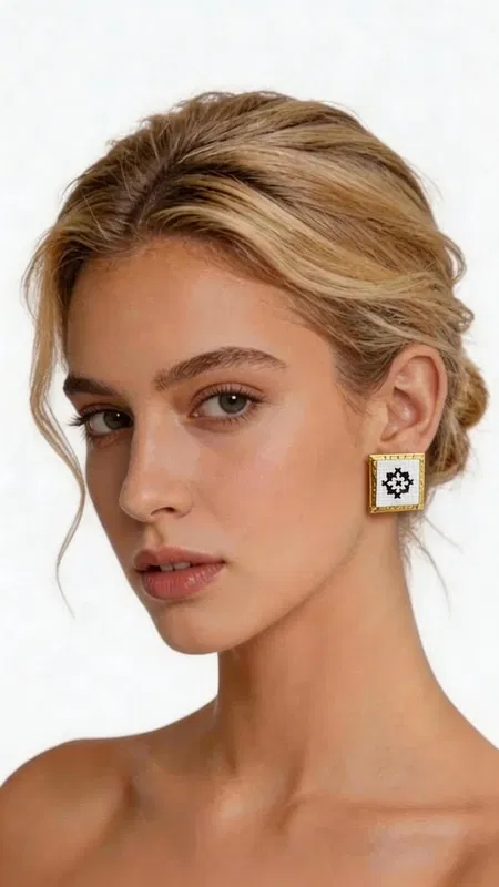 , Τα κεντητά σκουλαρίκια statement με γεωμετρικά σχέδια από χρυσοκλωστή σε άσπρο αποτελούν την τέλεια επιλογή για τη γυναίκα που αναζητά εντυπωσιακά και μοντέρνα κοσμήματα. Σχεδιασμένα από την Ελληνίδα Σχεδιάστρια Κοσμημάτων Αικατερίνη Χαλκιαδάκη, συνδυάζουν την παραδοσιακή τέχνη του κεντήματος με σύγχρονη αισθητική. Κάθε σκουλαρίκι διαθέτει τετράγωνη φόρμα με εκλεπτυσμένο γεωμετρικό μοτίβο κεντημένο με χρυσοκλωστή σε λευκή βάση. Το folklore design δημιουργεί μια μοναδική αντίθεση που προσδίδει κομψότητα και χαρακτήρα σε κάθε εμφάνιση. Τα χειροποίητα σκουλαρίκια είναι ιδανικά για γάμο, ειδικές εκδηλώσεις ή ως καθημερινό statement κόσμημα. Η υψηλή ποιότητα κατασκευής και τα επιλεγμένα υλικά εγγυώνται ανθεκτικότητα και άνεση στη χρήση. Το ελαφρύ τους βάρος τα καθιστά κατάλληλα για όλη τη μέρα, ενώ το μέγεθός τους προσδίδει τη σωστή δόση glamour χωρίς υπερβολή. Υλικό: Ορείχαλκος, Ύφασμα Φροντίστε τα σκουλαρίκια σας αποφεύγοντας την επαφή με νερό και αρώματα. Φυλάσσετε τα σε στεγνό μέρος για να διατηρήσουν τη λάμψη τους.