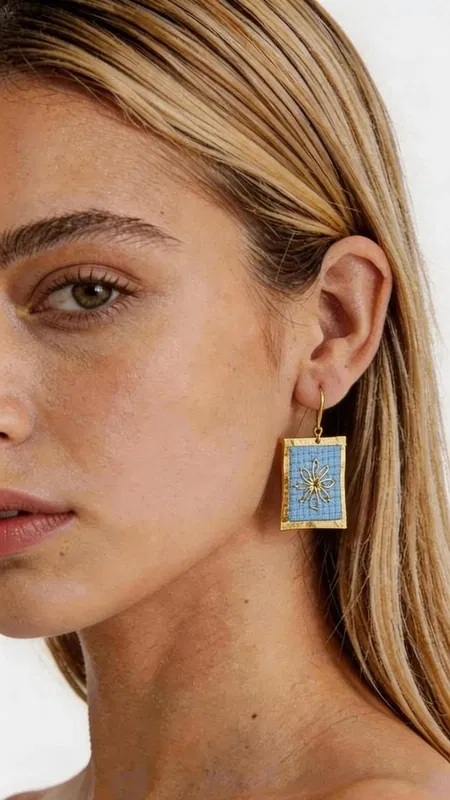 , Τα statement κεντητά σκουλαρίκια με γεωμετρικά σχέδια από χρυσοκλωστή σε γαλάζιο αποτελούν έναν μοναδικό συνδυασμό παραδοσιακής τέχνης και μοντέρνου σχεδιασμού. Σχεδιασμένα από την Ελληνίδα Σχεδιάστρια Κοσμημάτων Αικατερίνη Χαλκιαδάκη, αυτά τα εντυπωσιακά χειροποίητα σκουλαρίκια αναδεικνύουν την κομψότητα κάθε look με στιλ και χαρακτήρα. Η λεπτή κεντητική τεχνική με χρυσοκλωστή δημιουργεί ένα υπέροχο αποτέλεσμα που λαμπυρίζει διακριτικά, ενώ το γαλάζιο χρώμα προσφέρει μια φρεσκάδα που ταιριάζει τέλεια με θερινά και καλοκαιρινά outfit. Τα γεωμετρικά σχέδια προσδίδουν μοντέρνα αισθητική, κάνοντας τα εντυπωσιακά σκουλαρίκια ιδανική επιλογή για κάθε περίσταση. Τα χειροποίητα κεντητά σκουλαρίκια είναι τέλεια για γάμους, βαφτίσια, καλοκαιρινά πάρτι και κάθε ειδική στιγμή όπου θέλετε να ξεχωρίσετε. Συνδυάστε τα με λευκό ή μπλε ρούχα για να αναδείξετε το γαλάζιο τους χρώμα. Υλικό: Ορείχαλκος, Ύφασμα Φροντίστε τα σκουλαρίκια σας αποθηκεύοντάς τα σε στεγνό μέρος, μακριά από υγρασία και άμεση ηλιακή ακτινοβολία για να διατηρήσουν τη λάμψη τους.