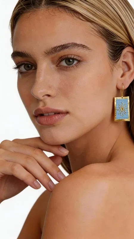 , Τα statement κεντητά σκουλαρίκια με γεωμετρικά σχέδια από χρυσοκλωστή σε γαλάζιο αποτελούν έναν μοναδικό συνδυασμό παραδοσιακής τέχνης και μοντέρνου σχεδιασμού. Σχεδιασμένα από την Ελληνίδα Σχεδιάστρια Κοσμημάτων Αικατερίνη Χαλκιαδάκη, αυτά τα εντυπωσιακά χειροποίητα σκουλαρίκια αναδεικνύουν την κομψότητα κάθε look με στιλ και χαρακτήρα. Η λεπτή κεντητική τεχνική με χρυσοκλωστή δημιουργεί ένα υπέροχο αποτέλεσμα που λαμπυρίζει διακριτικά, ενώ το γαλάζιο χρώμα προσφέρει μια φρεσκάδα που ταιριάζει τέλεια με θερινά και καλοκαιρινά outfit. Τα γεωμετρικά σχέδια προσδίδουν μοντέρνα αισθητική, κάνοντας τα εντυπωσιακά σκουλαρίκια ιδανική επιλογή για κάθε περίσταση. Τα χειροποίητα κεντητά σκουλαρίκια είναι τέλεια για γάμους, βαφτίσια, καλοκαιρινά πάρτι και κάθε ειδική στιγμή όπου θέλετε να ξεχωρίσετε. Συνδυάστε τα με λευκό ή μπλε ρούχα για να αναδείξετε το γαλάζιο τους χρώμα. Υλικό: Ορείχαλκος, Ύφασμα Φροντίστε τα σκουλαρίκια σας αποθηκεύοντάς τα σε στεγνό μέρος, μακριά από υγρασία και άμεση ηλιακή ακτινοβολία για να διατηρήσουν τη λάμψη τους.