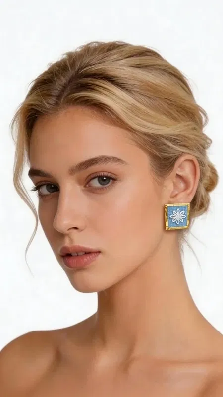 , Ανακαλύψτε τη μαγεία των κεντητών statement σκουλαρικιών με γεωμετρικά σχέδια από χρυσοκλωστή σε εντυπωσιακό γαλάζιο χρώμα. Αυτά τα εξαιρετικά χειροποίητα σκουλαρίκια, σχεδιασμένα από την Ελληνίδα Σχεδιάστρια Κοσμημάτων Αικατερίνη Χαλκιαδάκη, συνδυάζουν την παραδοσιακή τέχνη του κεντήματος με σύγχρονη αισθητική. Το κάθε σκουλαρίκι διακοσμείται με περίτεχνα γεωμετρικά μοτίβα που κεντήθηκαν με χρυσή κλωστή σε έντονο γαλάζιο υπόβαθρο, δημιουργώντας ένα μοναδικό κέντημα που θυμίζει την ελληνική παραδοσιακή τέχνη. Η τετράγωνη φόρμα και το χρυσό περίγραμμα προσθέτουν μία κομψή νότα που κάνει αυτά τα εντυπωσιακά σκουλαρίκια ιδανικά για κάθε περίσταση. Τα statement σκουλαρίκια αυτά είναι τέλεια για να συμπληρώσουν ένα νυφικό look, έναν επίσημο εορταστικό εμφανισμό ή ακόμα και ένα casual σύνολο που θέλετε να ξεχωρίσει. Η υψηλή ποιότητα κατασκευής και το πρωτότυπο σχέδιο τα καθιστούν ένα μοναδικό κομμάτι που θα απογειώσει το στυλ σας. Υλικό: Ορείχαλκος, Ύφασμα Φροντίστε τα με προσοχή, αποφεύγοντας την επαφή με νερό και αρώματα για τη διατήρηση των χρωμάτων.