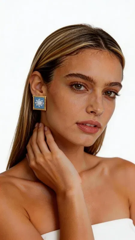 , Ανακαλύψτε τη μαγεία των κεντητών statement σκουλαρικιών με γεωμετρικά σχέδια από χρυσοκλωστή σε εντυπωσιακό γαλάζιο χρώμα. Αυτά τα εξαιρετικά χειροποίητα σκουλαρίκια, σχεδιασμένα από την Ελληνίδα Σχεδιάστρια Κοσμημάτων Αικατερίνη Χαλκιαδάκη, συνδυάζουν την παραδοσιακή τέχνη του κεντήματος με σύγχρονη αισθητική. Το κάθε σκουλαρίκι διακοσμείται με περίτεχνα γεωμετρικά μοτίβα που κεντήθηκαν με χρυσή κλωστή σε έντονο γαλάζιο υπόβαθρο, δημιουργώντας ένα μοναδικό κέντημα που θυμίζει την ελληνική παραδοσιακή τέχνη. Η τετράγωνη φόρμα και το χρυσό περίγραμμα προσθέτουν μία κομψή νότα που κάνει αυτά τα εντυπωσιακά σκουλαρίκια ιδανικά για κάθε περίσταση. Τα statement σκουλαρίκια αυτά είναι τέλεια για να συμπληρώσουν ένα νυφικό look, έναν επίσημο εορταστικό εμφανισμό ή ακόμα και ένα casual σύνολο που θέλετε να ξεχωρίσει. Η υψηλή ποιότητα κατασκευής και το πρωτότυπο σχέδιο τα καθιστούν ένα μοναδικό κομμάτι που θα απογειώσει το στυλ σας. Υλικό: Ορείχαλκος, Ύφασμα Φροντίστε τα με προσοχή, αποφεύγοντας την επαφή με νερό και αρώματα για τη διατήρηση των χρωμάτων.