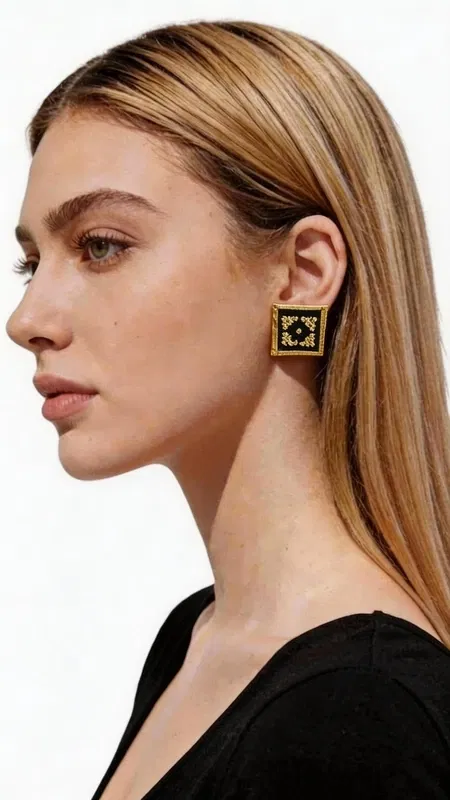 , Ξεχωρίστε με αυτά τα εντυπωσιακά statement κεντητά σκουλαρίκια που συνδυάζουν την παραδοσιακή ελληνική τέχνη του κεντήματος με σύγχρονο γεωμετρικό design. Σχεδιασμένα από την Ελληνίδα Σχεδιάστρια Κοσμημάτων Αικατερίνη Χαλκιαδάκη, αυτά τα μοναδικά χειροποίητα σκουλαρίκια φέρουν έναν πλούσιο χρυσόκλωστο κεντητό σχεδιασμό πάνω σε κομψό μαύρο φόντο. Κάθε σκουλαρίκι αποτελεί ένα μικρό έργο τέχνης με περίπλοκα γεωμετρικά μοτίβα που δημιουργούν μια εκπληκτική οπτική αίσθηση. Η χρυσή κλωστή λάμπει υπέροχα πάνω στη μαύρη βάση, προσφέροντας έναν εντυπωσιακό συνδυασμό που ταιριάζει τόσο σε καθημερινές όσο και σε επίσημες εμφανίσεις. Αυτά τα μοντέρνα κρεμαστά σκουλαρίκια είναι ιδανικά για γυναίκες που αγαπούν τα πρωτότυπα κοσμήματα με ελληνικό χαρακτήρα. Το τετράγωνο σχήμα τους προσφέρει μια σύγχρονη αισθητική, ενώ η κεντητή λεπτομέρεια φέρνει την παράδοση στο προσκήνιο. Υλικό: Ορείχαλκος, Ύφασμα Φροντίστε τα σκουλαρίκια σας αποθηκεύοντάς τα σε στεγνό μέρος και αποφεύγοντας την επαφή με υγρασία και χημικά προϊόντα.