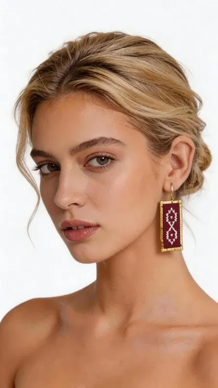 , Τα statement κεντητά σκουλαρίκια με γεωμετρικά σχέδια σε μπορντό χρώμα αποτελούν τον τέλειο συνδυασμό παραδοσιακής τέχνης και σύγχρονης αισθητικής. Κατασκευασμένα από χρυσοκλωστή υψηλής ποιότητας, αυτά τα εντυπωσιακά σκουλαρίκια έχουν σχεδιαστεί από την Ελληνίδα Σχεδιάστρια Κοσμημάτων Αικατερίνη Χαλκιαδάκη, αποτυπώνοντας την αυθεντική ελληνική κοσμηματοτεχνία. Τα ορθογώνια κεντητά σκουλαρίκια διαθέτουν πολύπλοκα γεωμετρικά μοτίβα που δημιουργούν μια εκλεπτυσμένη vintage αισθητική. Το βαθύ μπορντό χρώμα συνδυάζεται αρμονικά με τις χρυσές λεπτομέρειες, δημιουργώντας ένα luxurious αποτέλεσμα που ταιριάζει τέλεια σε κάθε περίσταση. Η χειροποίητη κατασκευή εγγυάται την μοναδικότητα κάθε κομματιού, ενώ το ελαφρύ τους βάρος τα καθιστά ιδανικά για όλη την ημέρα. Αυτά τα boho σκουλαρίκια αποτελούν την τέλεια επιλογή για γάμους, ειδικές εκδηλώσεις ή για να προσθέσετε μια δόση κομψότητας στην καθημερινότητά σας. Υλικό: Ορείχαλκος, Ύφασμα Φροντίστε τα σκουλαρίκιά σας αποφεύγοντας την επαφή με νερό και αρώματα. Φυλάσσετε τα σε στεγνό μέρος για να διατηρήσετε τη λάμψη τους.