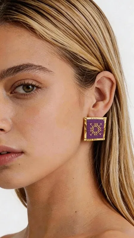 , Τα statement σκουλαρίκια κεντητά με χρυσοκλωστή σε εντυπωσιακό μπορντό χρώμα αποτελούν την ιδανική επιλογή για γυναίκες που αναζητούν μοναδικό στυλ και κομψότητα. Αυτά τα χειροποίητα σκουλαρίκια, σχεδιασμένα από την Ελληνίδα Σχεδιάστρια Κοσμημάτων Αικατερίνη Χαλκιαδάκη, διακρίνονται για τα εντυπωσιακά γεωμετρικά σχέδια και την υψηλή ποιότητα κατασκευής. Η τετράγωνη φόρμα με τα χρυσά περιγράμματα και την πλούσια κεντητή επιφάνεια δημιουργεί έναν μοναδικό συνδυασμό παραδοσιακής τεχνικής και μοντέρνου design. Το βαθύ μπορντό χρώμα προσφέρει πολυτέλεια και κομψότητα, ενώ οι χρυσές λεπτομέρειες προσδίδουν λάμψη και φινέτσα. Αυτά τα εντυπωσιακά σκουλαρίκια είναι ιδανικά για ειδικές στιγμές όπως γάμους, εκδηλώσεις ή βραδινές εξόδους, αλλά μπορούν επίσης να αναβαθμίσουν και το καθημερινό σας look. Η ελληνική χειροτεχνία και η προσοχή στη λεπτομέρεια τα καθιστούν μοναδικά κομμάτια που θα ξεχωρίζουν από τη συλλογή σας. Υλικό: Ορείχαλκος, Ύφασμα Φροντίστε τα με προσοχή, αποφεύγοντας την επαφή με νερό και αρώματα για να διατηρήσουν την αίγλη τους.