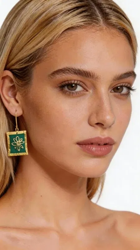 , Τα εντυπωσιακά κεντητά σκουλαρίκια statement σε πράσινο χρώμα προσφέρουν μια μοναδική αισθητική που συνδυάζει την παραδοσιακή τέχνη του κεντήματος με σύγχρονο γεωμετρικό σχεδιασμό. Κάθε κομμάτι, σχεδιασμένο από την Ελληνίδα Σχεδιάστρια Κοσμημάτων Αικατερίνη Χαλκιαδάκη, αποτελεί έργο τέχνης που μετατρέπει κάθε εμφάνιση σε ξεχωριστή. Η χρυσοκλωστή που χρησιμοποιείται δημιουργεί εκθαμβωτικές αντανακλάσεις φωτός, ενώ το έντονο πράσινο χρώμα προσθέτει φρεσκάδα και ζωντάνια. Τα τετράγωνα κεντητά στοιχεία με το κεντρικό γεωμετρικό μοτίβο σε χρυσές αποχρώσεις δημιουργούν μια εκλεπτυσμένη αντίθεση που τραβά τα βλέμματα. Ιδανικά για ιδιαίτερες στιγμές και εκδηλώσεις, αυτά τα χειροποίητα σκουλαρίκια συμπληρώνουν τέλεια τόσο κλασικά όσο και μοντέρνα σύνολα. Η άνετη εφαρμογή και το ελαφρύ βάρος τα καθιστούν κατάλληλα για όλη τη μέρα. Υλικό: Ορείχαλκος, Ύφασμα Για τη διατήρηση της ομορφιάς τους, φυλάξτε τα σε στεγνό μέρος μακριά από άμεσο ήλιο.