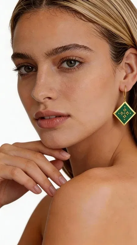 , Αυτά τα εντυπωσιακά κεντητά σκουλαρίκια statement με γεωμετρικό σχέδιο θα γίνουν το απόλυτο αξεσουάρ για κάθε σας εμφάνιση. Η τετραγωνική τους φόρμα σε πράσινη απόχρωση με χρυσές λεπτομέρειες δημιουργεί μια μοναδική αισθητική που συνδυάζει το μοντέρνο στυλ με την παραδοσιακή τέχνη της κεντητικής. Σχεδιασμένα από την Ελληνίδα Σχεδιάστρια Κοσμημάτων Αικατερίνη Χαλκιαδάκη, αυτά τα χειροποίητα σκουλαρίκια ξεχωρίζουν για την εξαιρετική ποιότητα της χρυσοκλωστής και τη σύγχρονη ερμηνεία των γεωμετρικών μοτίβων. Το πράσινο χρώμα προσδίδει φρεσκάδα και ζωντάνια, ενώ οι χρυσές λεπτομέρειες αναδεικνύουν την κομψότητα του σχεδίου. Τα κρεμαστά αυτά σκουλαρίκια είναι ιδανικά για βραδινές εξόδους, ειδικές περιστάσεις ή όταν θέλετε να προσθέσετε μια δόση στυλ στην καθημερινή σας εμφάνιση. Η μοναδική τους φόρμα και το χρωματικό τους σχήμα τα καθιστούν απόλυτα versatile, συνδυάζονται τέλεια με μονόχρωμα outfits και προσδίδουν έναν εντυπωσιακό χαρακτήρα. Υλικό: Ορείχαλκος, Ύφασμα Φροντίστε τα σκουλαρίκια σας αποθηκεύοντάς τα σε στεγνό μέρος και καθαρίζοντάς τα απαλά με μαλακό πανί.