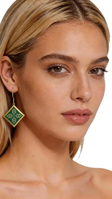 Εντυπωσιακά κεντητά σκουλαρίκια statement που συνδυάζουν την παραδοσιακή τέχνη του κεντήματος με σύγχρονο γεωμετρικό design. Σχεδιασμένα από την Ελληνίδα Σχεδιάστρια Κοσμημάτων Αικατερίνη Χαλκιαδάκη, αυτά τα μοναδικά χειροποίητα σκουλαρίκια σε πράσινο χρώμα θα γίνουν το κεντρικό σημείο κάθε σας εμφάνισης. Το εκλεπτυσμένο ρομβοειδές σχήμα με τα λεπτομερή κεντητά μοτίβα από χρυσοκλωστή δημιουργεί μια κομψή αντίθεση με το έντονο πράσινο χρώμα. Κάθε σκουλαρίκι είναι χειροποίητο με ιδιαίτερη προσοχή στη λεπτομέρεια, συνδυάζοντας folklore design elements με μοντέρνα αισθητική. Ιδανικά για γάμο, ειδικές εκδηλώσεις ή όταν θέλετε να προσθέσετε μια δόση χρώματος και κομψότητας στην καθημερινότητά σας. Το ελαφρύ τους βάρος τα καθιστά άνετα για ολοήμερη χρήση. Συντηρήστε τα σκουλαρίκια σε στεγνό χώρο, αποφεύγοντας την επαφή με νερό και χημικά προϊόντα για να διατηρήσουν τη λάμψη και την ομορφιά τους.