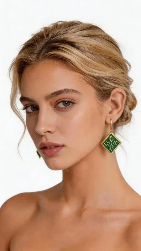 , Εντυπωσιακά κεντητά σκουλαρίκια statement που συνδυάζουν την παραδοσιακή τέχνη του κεντήματος με σύγχρονο γεωμετρικό design. Σχεδιασμένα από την Ελληνίδα Σχεδιάστρια Κοσμημάτων Αικατερίνη Χαλκιαδάκη, αυτά τα μοναδικά χειροποίητα σκουλαρίκια σε πράσινο χρώμα θα γίνουν το κεντρικό σημείο κάθε σας εμφάνισης. Το εκλεπτυσμένο ρομβοειδές σχήμα με τα λεπτομερή κεντητά μοτίβα από χρυσοκλωστή δημιουργεί μια κομψή αντίθεση με το έντονο πράσινο χρώμα. Κάθε σκουλαρίκι είναι χειροποίητο με ιδιαίτερη προσοχή στη λεπτομέρεια, συνδυάζοντας folklore design elements με μοντέρνα αισθητική. Ιδανικά για γάμο, ειδικές εκδηλώσεις ή όταν θέλετε να προσθέσετε μια δόση χρώματος και κομψότητας στην καθημερινότητά σας. Το ελαφρύ τους βάρος τα καθιστά άνετα για ολοήμερη χρήση. Συντηρήστε τα σκουλαρίκια σε στεγνό χώρο, αποφεύγοντας την επαφή με νερό και χημικά προϊόντα για να διατηρήσουν τη λάμψη και την ομορφιά τους.