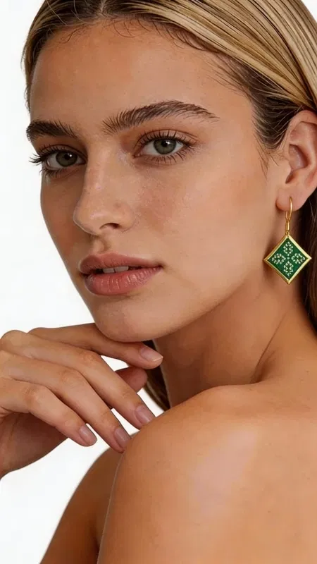 , Εντυπωσιακά κεντητά σκουλαρίκια statement που συνδυάζουν την παραδοσιακή τέχνη του κεντήματος με σύγχρονο γεωμετρικό design. Σχεδιασμένα από την Ελληνίδα Σχεδιάστρια Κοσμημάτων Αικατερίνη Χαλκιαδάκη, αυτά τα μοναδικά χειροποίητα σκουλαρίκια σε πράσινο χρώμα θα γίνουν το κεντρικό σημείο κάθε σας εμφάνισης. Το εκλεπτυσμένο ρομβοειδές σχήμα με τα λεπτομερή κεντητά μοτίβα από χρυσοκλωστή δημιουργεί μια κομψή αντίθεση με το έντονο πράσινο χρώμα. Κάθε σκουλαρίκι είναι χειροποίητο με ιδιαίτερη προσοχή στη λεπτομέρεια, συνδυάζοντας folklore design elements με μοντέρνα αισθητική. Ιδανικά για γάμο, ειδικές εκδηλώσεις ή όταν θέλετε να προσθέσετε μια δόση χρώματος και κομψότητας στην καθημερινότητά σας. Το ελαφρύ τους βάρος τα καθιστά άνετα για ολοήμερη χρήση. Συντηρήστε τα σκουλαρίκια σε στεγνό χώρο, αποφεύγοντας την επαφή με νερό και χημικά προϊόντα για να διατηρήσουν τη λάμψη και την ομορφιά τους.