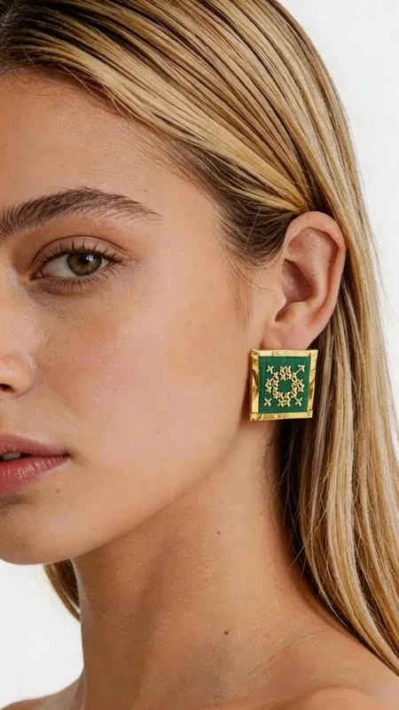 Ξεχωρίστε με αυτά τα εντυπωσιακά statement σκουλαρίκια κεντητά με χρυσοκλωστή σε έντονο πράσινο χρώμα που συνδυάζουν την παραδοσιακή τέχνη του κεντήματος με τη σύγχρονη αισθητική. Σχεδιασμένα από την Ελληνίδα Σχεδιάστρια Κοσμημάτων Αικατερίνη Χαλκιαδάκη, αυτά τα χειροποίητα σκουλαρίκια φέρουν γεωμετρικά σχέδια που εμπνέονται από το ελληνικό folklore. Κάθε σκουλαρίκι είναι μοναδικό έργο τέχνης, κεντημένο με λεπτομέρεια και αγάπη. Το πλούσιο πράσινο χρώμα σε συνδυασμό με τις χρυσές λεπτομέρειες δημιουργούν έναν εντυπωσιακό συνδυασμό που ταιριάζει τόσο σε καθημερινά όσο και σε επίσημα looks. Η τετραγωνική φόρμα τους προσδίδει μοντέρνα αισθητική, ενώ η χειροποίητη κατασκευή εγγυάται την υψηλή ποιότητα. Ιδανικά για κάθε περίσταση, από casual εμφανίσεις έως γάμους και επίσημες βραδινές εκδηλώσεις. Συνδυάστε τα με μονόχρωμα outfits για να αναδείξετε την ομορφιά τους ή δημιουργήστε bohemian looks που εκφράζουν την προσωπικότητά σας. Υλικό: Ορείχαλκος, Ύφασμα Φροντίδα: Φυλάσσετε σε στεγνό μέρος μακριά από υγρασία και άμεση ηλιακή ακτινοβολία.